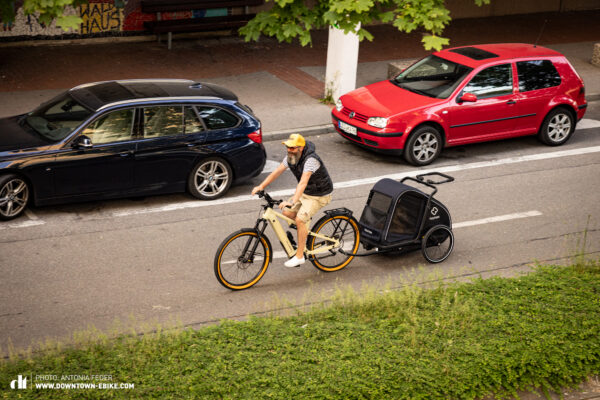 Oli fährt hier auf der Straße in der Stadt mit anderen Autos und Fahrrad-Hundeanhänger.